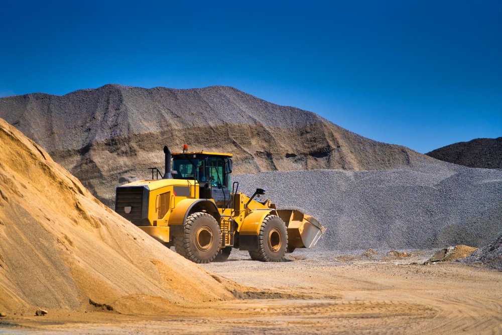 Image of an excavator with a pile of rocks