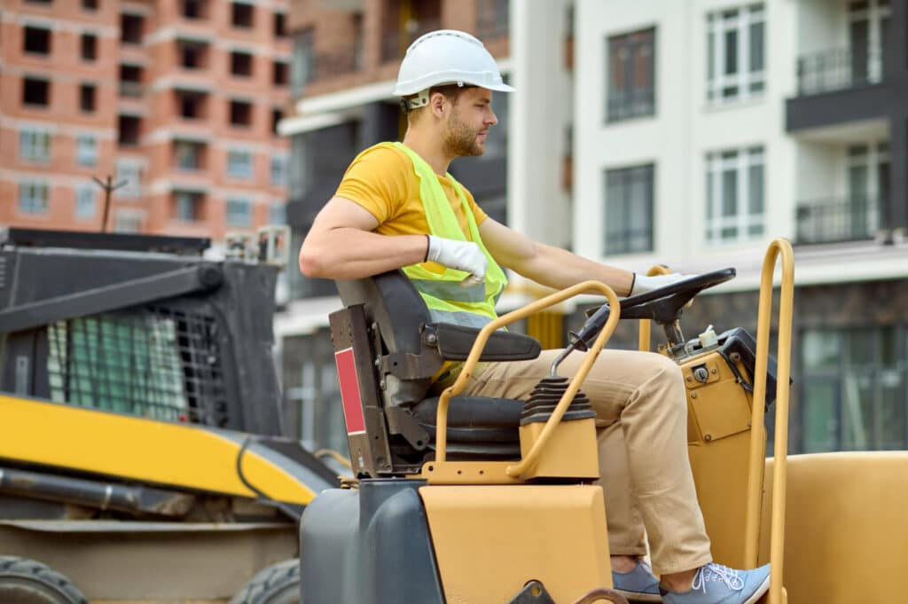 Image of a man operating a post driver attached to a excavator